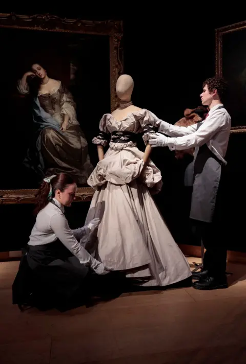 John Phillips/Getty Images Technicians adjust a dress from Vivienne Westwood’s collection at Christie's auction house in London