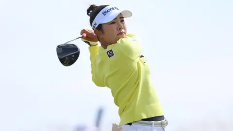 PA Miyu Yamashita wearing a yellow jumper and white trousers