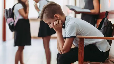 Getty Images Boy sits along in corridor