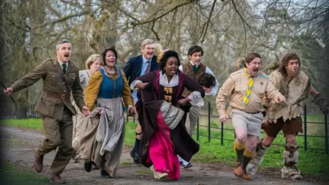 BBC/Monumental Television Scene from the TV sitcom Ghosts with the characters running towards the gate