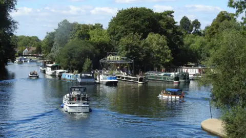 A shot of D'Oyly Carte Island taken from the Thames with boats surrounding the island.