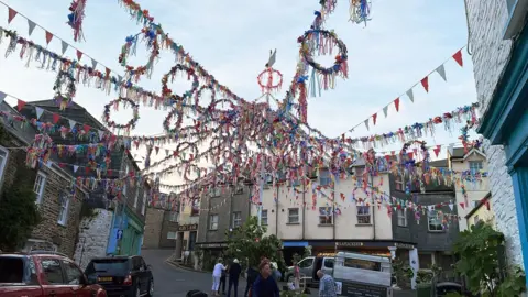 A town square with May Day decorations including bunting and a may pole.