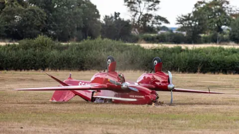 Sprite Photography A red DH.88 Comet is lying on its roof with a damaged nose.