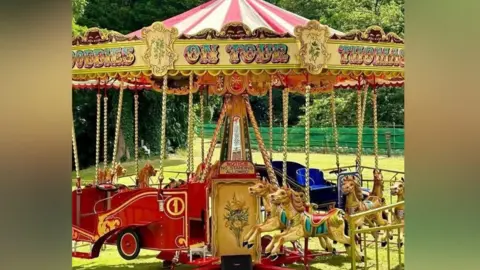 A vintage fairground roundabout ride with carousel horses and carriages. 
