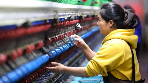 An employee operates a machine at a silk production enterprise on November 17, 2025 in Chongqing, China