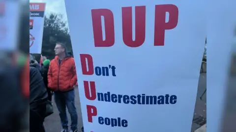 Placard saying 'DUP - Don't Underestimate People'