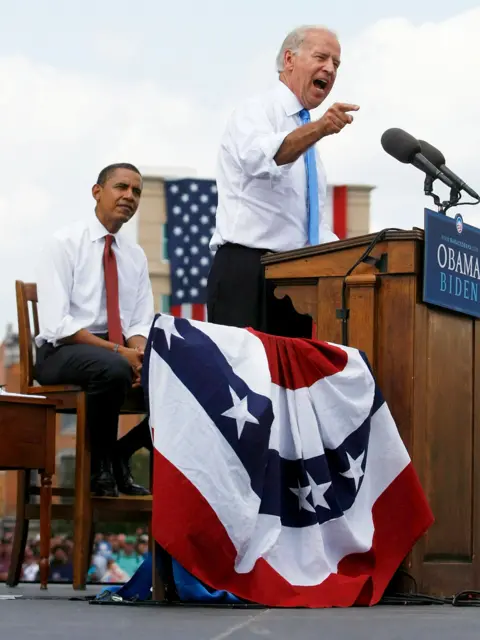 Joe Raedle / Getty Images Barak Obama listens Joe Biden on stage