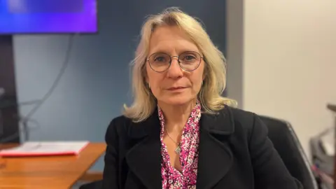 BBC Deputy Elaine Millar. Ms Millar is wearing glasses, a pink blouse and black jacket. 