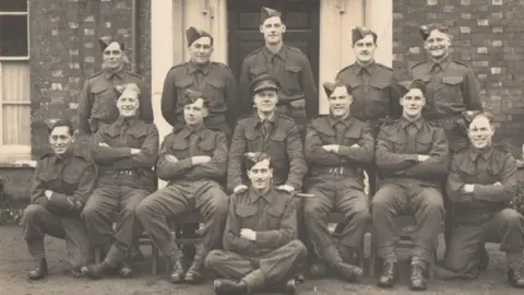 Joanna Burri-Weaver Black and White image of the members of the Dorset Regiment Scout Section of Auxiliary Units outside Chestnut House in Blandford. Maj Weaver is middle row and centre.