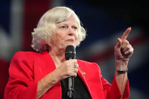 La portavoz de Reform UK sobre inmigración y justicia, Ann Widdecombe, lleva una chaqueta roja y pronuncia un discurso en 2024.