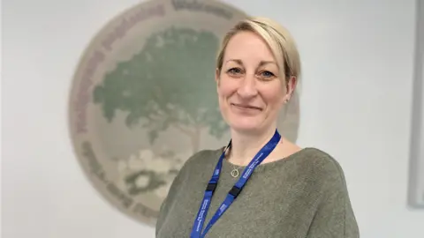 Somerset NHS Foundation Trust Women with blonde hairsbreadth  and bluish  lanyard smiling astatine  the camera