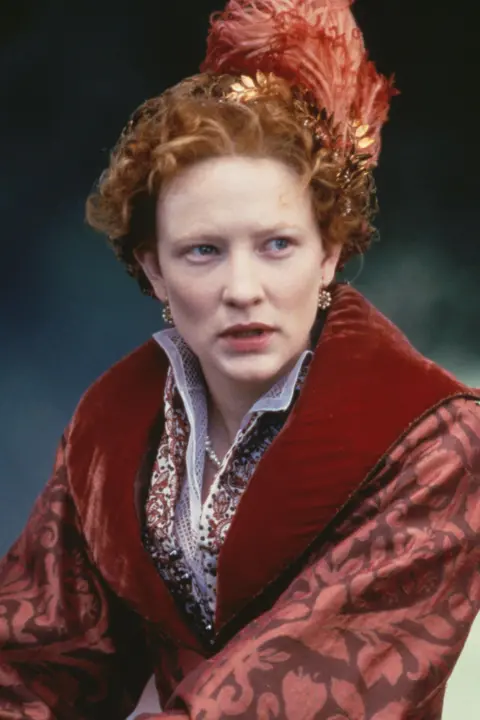 AFP via Getty Images Cate Blanchett dressed in crimson-coloured period dress and appears with long red hair, pictured on the set of the film Elizabeth.