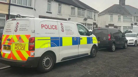 A white terraced house with a police van outside