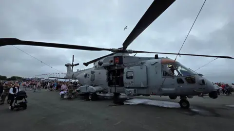A military helicopter on Plymouth Hoe surrounded by people.