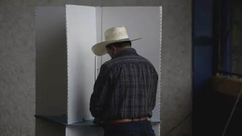 Getty Images A Guatemalan man wearing a cowboy hat casts his cote in the August 2019 election