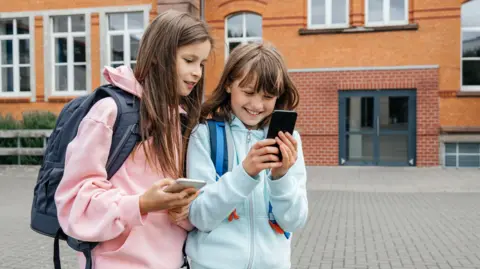 Two young girls look at a phone