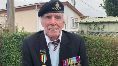 Tommy Clough standing outside wearing his military medals and cap