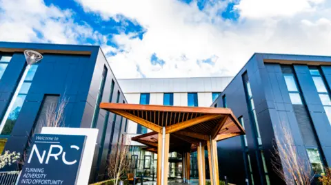 A wooden structure out the front of a new rehabilitation centre with black and white cladding