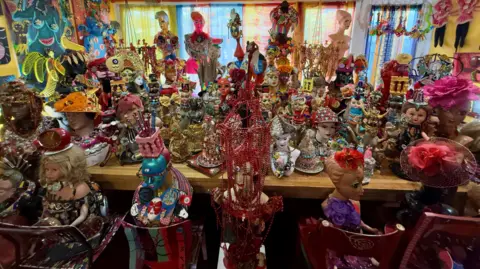 A curated display of dolls heads and sculptures on a table