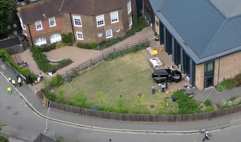 PA Media Aerial view of the scene of the black Land Rover crashed into the school playground with police and equipment strewn on the ground