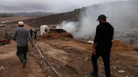 EPA Palestinians put out a fire following an attack by Israeli settlers in al-Ladain, near Beit Lid village, in the occupied West Bank (11 November 2025)
