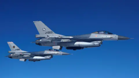 Reuters Two F-16 jets painted gray and blue flying in the blue sky