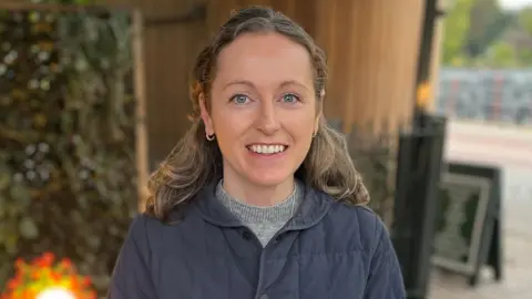 Gem O'Reilly/BBC Moira Jordan in a grey jumper and navy blue jacket. 