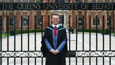 Tim Neill Dr Tim Neill stands at the gates of Queen's University Belfast on the day of his graduation