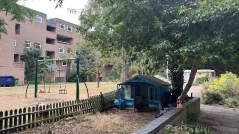 Image of an empty play park with a block of flats in the background.