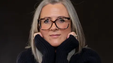 Victoria Sedgwick Kay Backhorse wearing glasses and a black polo neck jumper