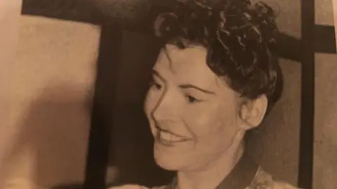 Ecclesfield Priory Players A black and white close-up of a woman, Jean Dalby, taken in the 1970s.
Her hair is pinned up and she smiles.