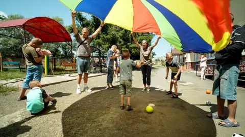 Simon Cooke (holding parachute, left) with Ruth Wyn Williams and children at the orphanage