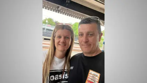 Emma Parker A selfie of Emma and Nathan. She is on the right, with an Oasis t-shirt and he is on the left, also wearing an Oasis t-shirt and showing an access pass to an Oasis concert in London. They are standing on a train platform. 