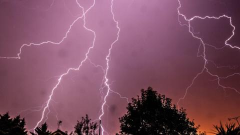 Fork lightning across a purple and orange sky