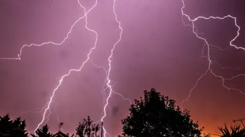 Fork lightning across a purple and orange sky