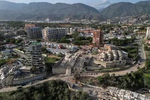 AFP via Getty Images This aerial view shows collapsed buildings in Catia La Mar, La Guaira state, Venezuela, shows multiple collapsed buildings and rubble sitting in a valley with a backdrop of green mountains 
