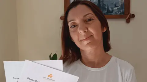 Now Teach A woman with brown hair holding her GCSE certificates.