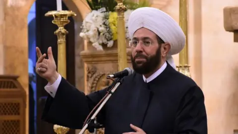 File photo showing Syria's then grand mufti, Ahmed Hassoun, speaking inside the Cathedral of Mar Elias in the northern Syrian city of Aleppo on 20 July 2020