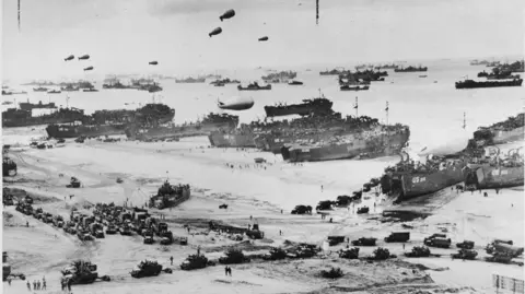 LIBRARY OF CONGRESS A black and white photo of allied forces landing on Normany beaches, including tanks and ships