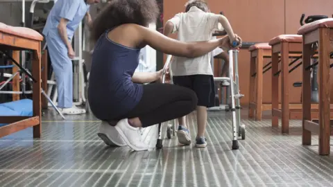 Getty Images Woman helping disabled child