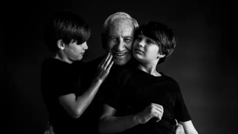 National Portrait Gallery/Ancestry In December 2021 these children lost their grandmother and their grandfather lost his wife of of 52 years. Due to the pandemic the kids had not seen their grandmother in over 2 years. Those 2 years have turned into forever. Granddad was finally able to come visit and we took the opportunity to make sure that they were photographed together, because these photographs will last forever. Their bond is beautiful and the love grandchildren can give helps mend a broken heart just a little. Photo by Kayleigh Tricker