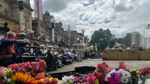 Anna Jameson/BBC sit in silence outside the Southabport town hall