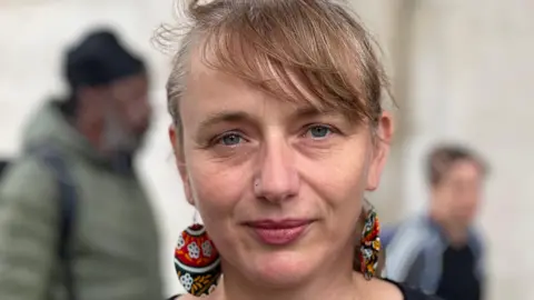 Close up shot of Emma Reynolds who is wearing large disc earrings