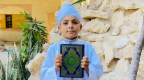 Família al-Najjar Adam al-Najjar segura um Alcorão enquanto posa para uma foto