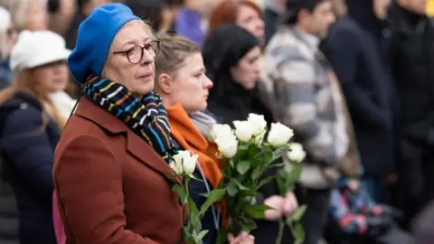 EPA/Shutterstock A woman in Zurich holds flowers during a national day of mourning in Switzerland. Photo: 9 January 2026