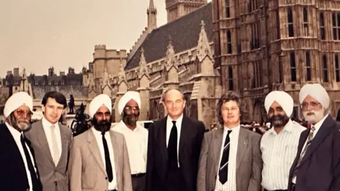 Handout A group of eight men, five of them wearing turbans, outside the Houses of Parliament. Sepia photograph.