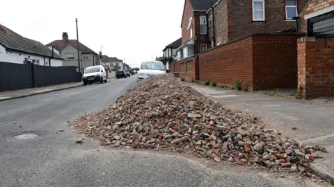 LDRS A large pile of bricks dumped by the curb on Sherburn Street in Cleethorpes. Houses and cars are seen in the background.