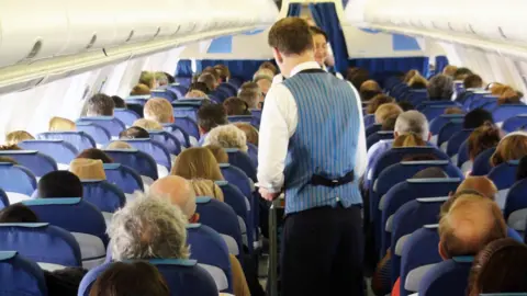 Getty Images Passengers and cabin crew in plane
