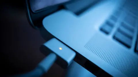 Getty Images A Macbook with a charger plugged in