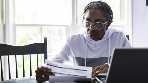 Getty Images Woman looking at bills